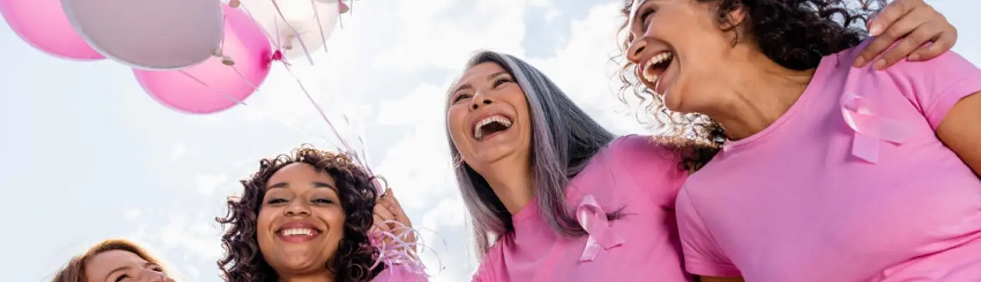 Friends in pink tees laughing with balloons at a Go Pink event