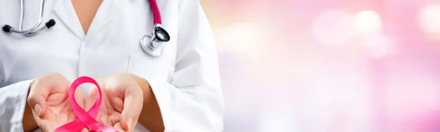 A healthcare provider in a white coat holding a pink awareness ribbon