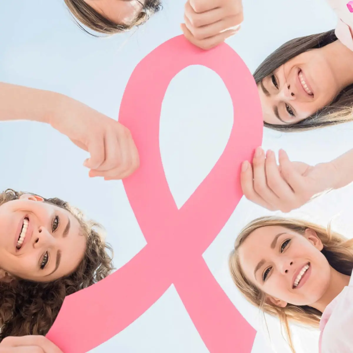 A group holding up a large pink breast cancer awareness ribbon