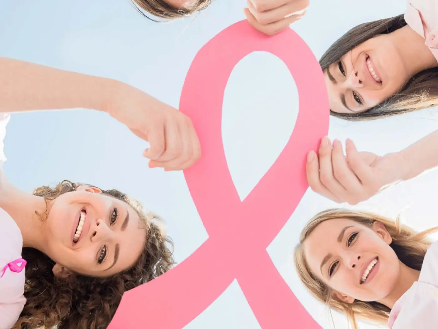 A group holding up a large pink breast cancer awareness ribbon